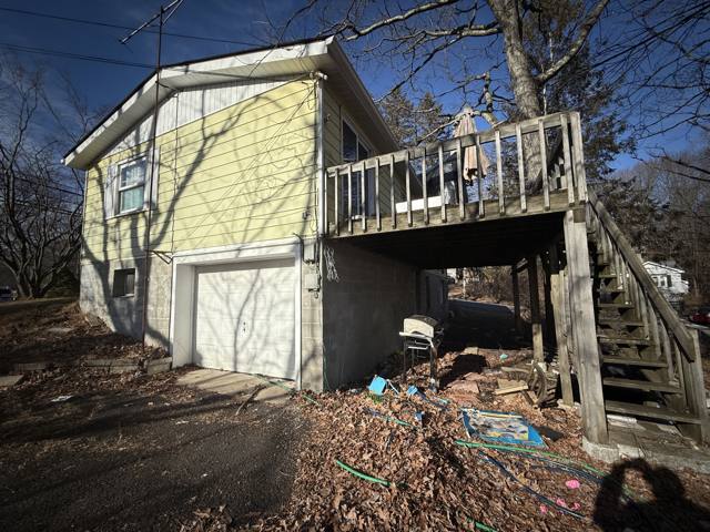 Before: back of the house with the garage door and deck stairs